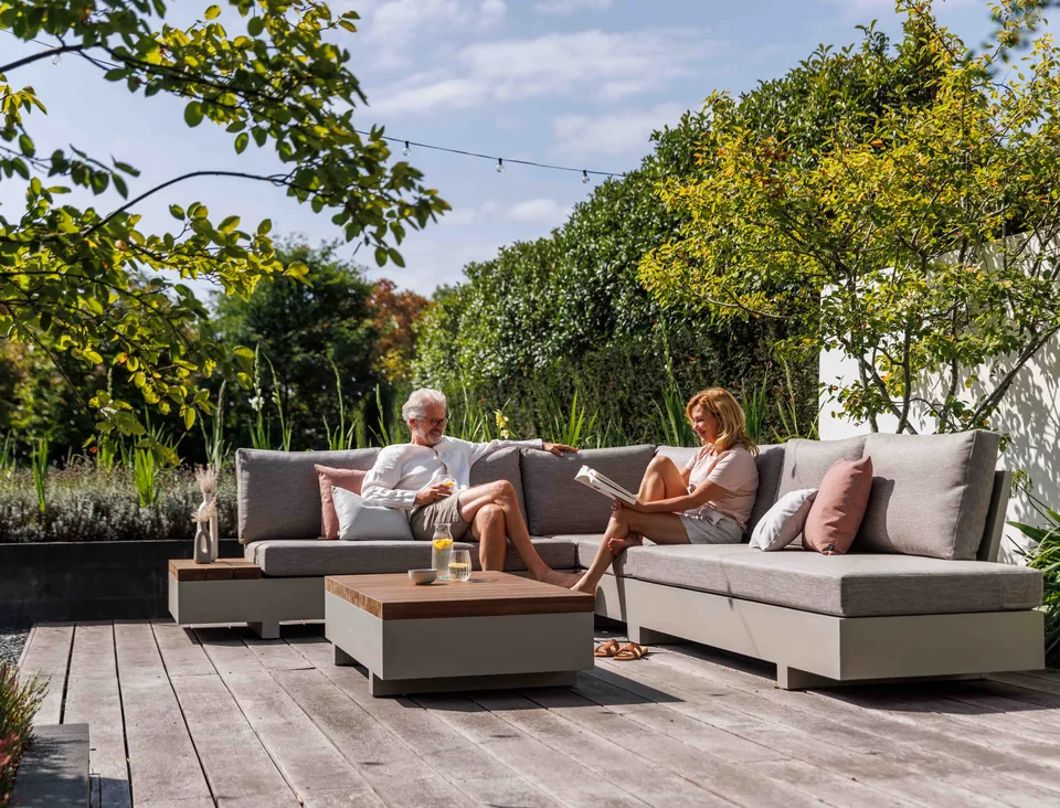 Couple relaxing on a grey lounge set on a wooden deck