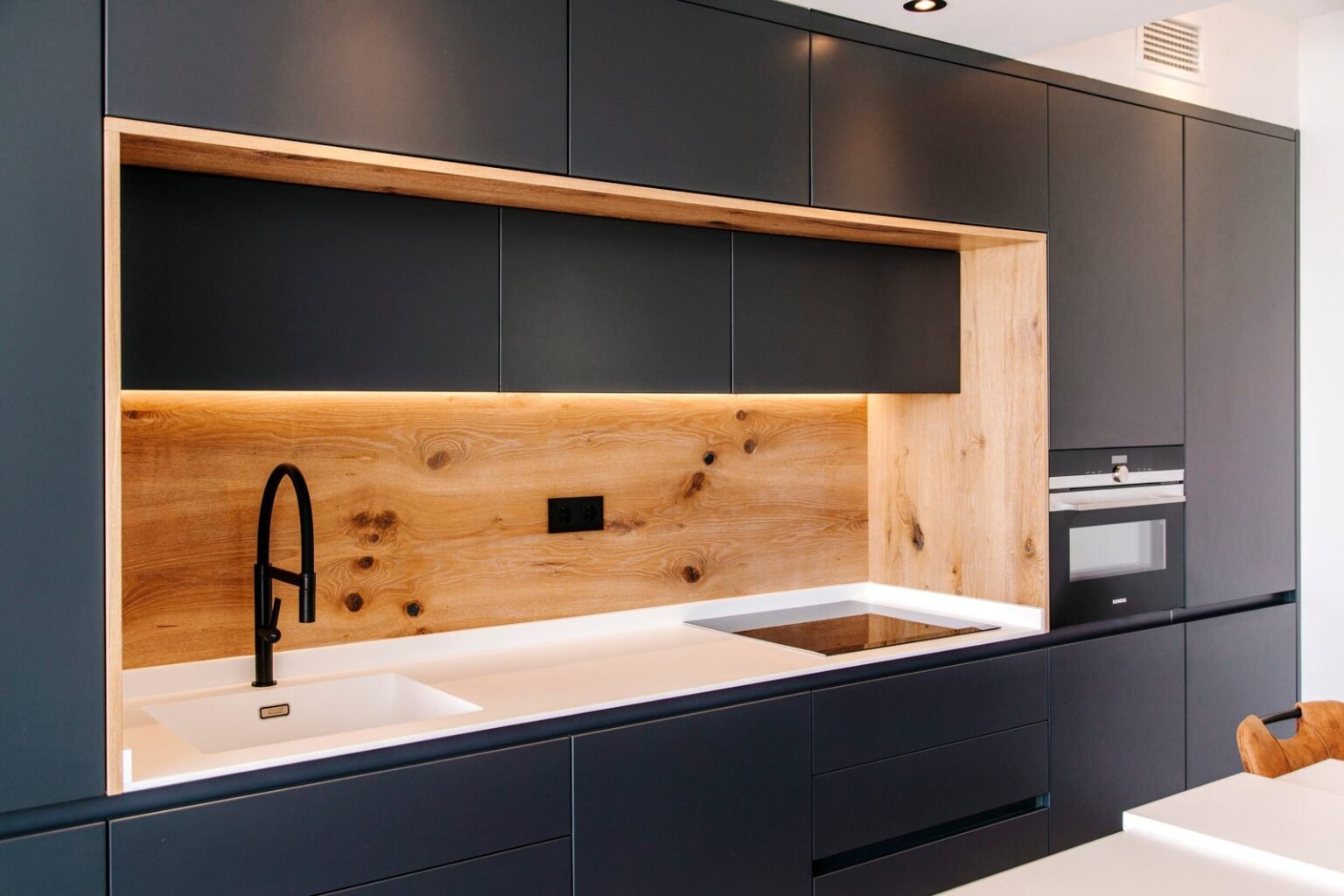 Dark custom kitchen with oak backsplash and integrated lighting by Bella Kitchens